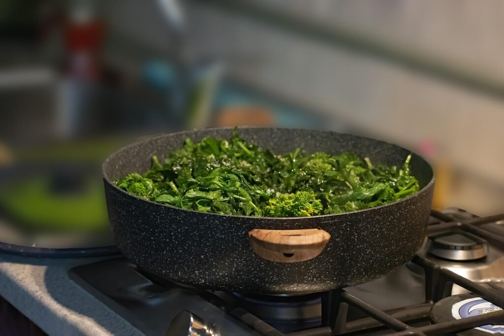 Cime di rapa e broccoletti verdi che cuociono in una padella sul fuoco in cucina